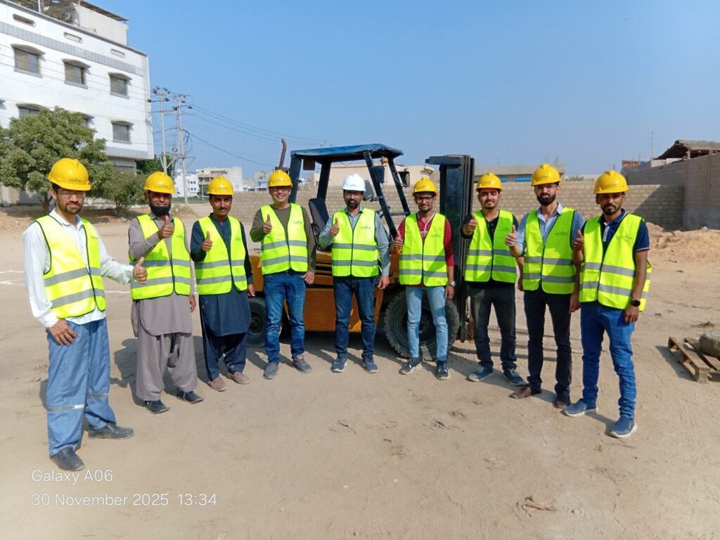 SafeOSH forklift operator class in hi-vis vests and hard hats beside a forklift